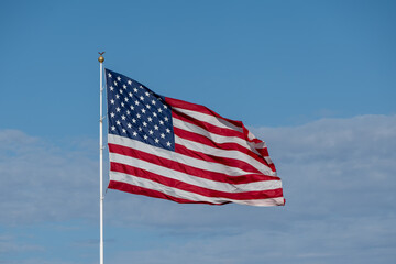 Fototapeta premium American Flag Waving Against Blue Sky with Copy Space and Clear Day Lighting