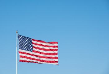 Fototapeta premium United States Flag Waving in Wind on Clear Blue Sky Background