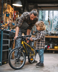 Father and child watching mechanic inspect small bicycle brakes in local repair shop