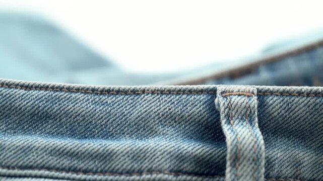 Close up of denim belt loop and stitching detail on jeans.
