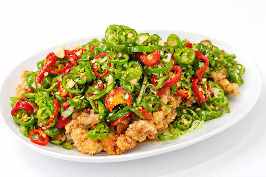 Crispy deep-fried chicken with sliced green chili peppers on a white plate