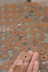 Hand Picking Vintage Holed Coin from a Large Hoard © Mas