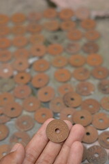 Hand Picking a Vintage Holed Coin from a Large Hoard of Currency © Mas