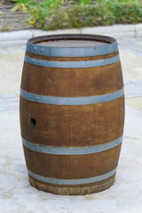 Fototapeta premium Traditional oak barrel with metal hoops standing on a stone patio, ready for aging wine, beer, or other alcoholic beverages, representing craftsmanship and storage