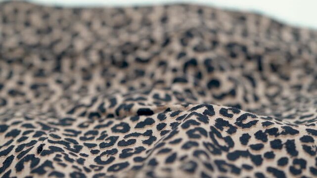 Close up of leopard print fabric texture with soft folds and pattern.