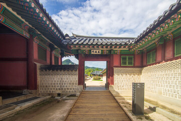 Obraz premium Majestic Korean palace architecture with symmetrical stone courtyard and layered tiled roof under dramatic sky, traditional Asian heritage landmark, cultural travel destination concept