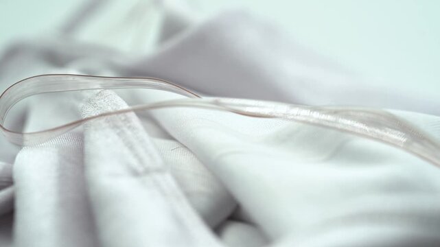 Close up of clear plastic dress strap on white fabric detail.