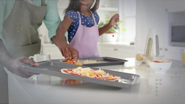 Father placing tray, guiding daughter sprinkling peppers on pizzas, animated halos guiding hands