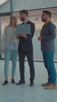 Real estate professionals collaboratively inspecting office space using laptops and discussing details