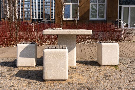 Modern stone chess table with concrete stools in a contemporary residential courtyard, featuring board games for outdoor recreation in a stylish urban environment
