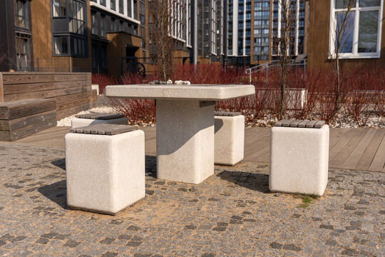 Modern stone chess table with concrete stools in a contemporary residential courtyard, featuring board games for outdoor recreation in a stylish urban environment