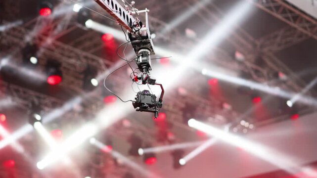 Professional camera crane filming concert stage with dynamic lighting effects and smoke.