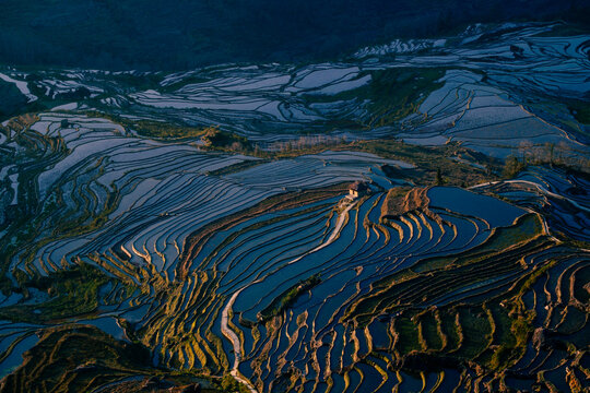 Sunset over the historic Hani rice terraces, with a Hani village overlooking the centuries-old landscape.