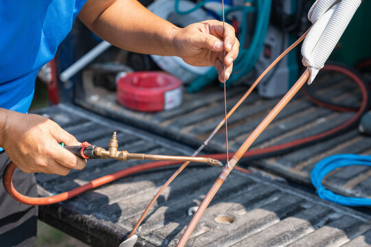 Technician soldering and brazing copper pipes for air conditioning system installation, Professional HVAC worker using blow torch to join copper tubing on a pickup truck bed