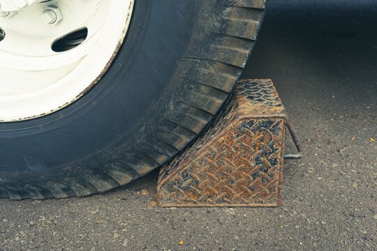 Heavy duty metal wheel chock securing large truck tire.