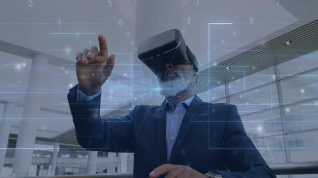 Senior executive in atrium raising hand, wearing VR and manipulating hologram business analytics