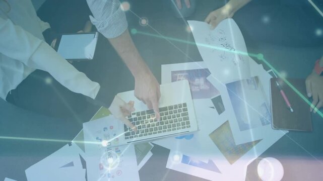 Single hand starting on trackpad three colleagues pointing, tapping, spreading pages planning steps