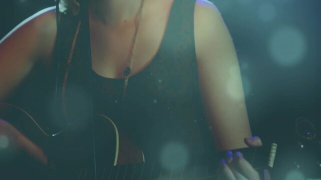 Female singer playing guitar camera pulling back showing her singing at mic for music amid haze