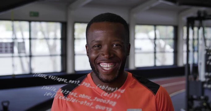 Male trainer reacting to scrolling code overlay showing performance data across chest in sports gym