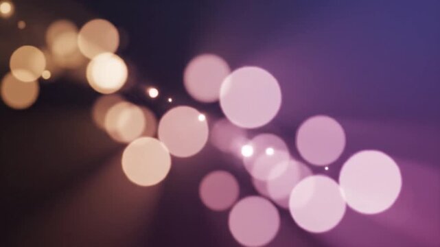Soft glowing bokeh lights drifting across a blurred purple and gold background, creating a dreamy, elegant, and atmospheric abstract motion effect.