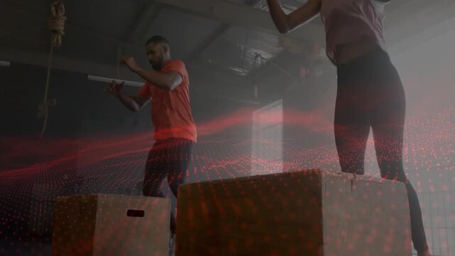 Man and woman swinging arms starting synced box jumps for fitness power, red grid overlaying bodies
