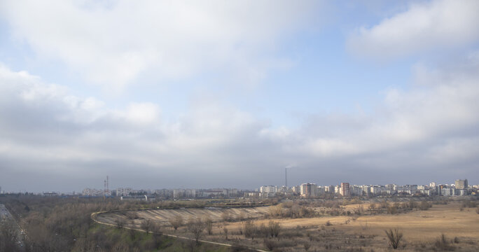 Panoramic wide-angle view of the Bucharest skyline featuring the Vacaresti Nature Park wetlands and distant residential apartment blocks under a cloudy sky