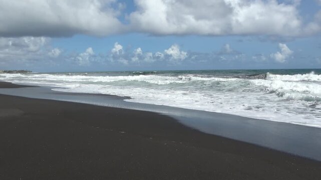 Eine atmosph&auml;rische Aufnahme eines unber&uuml;hrten vulkanischen schwarzen Sandstrandes in der Karibik