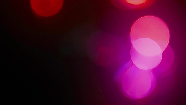 Abstract pink blurry bokeh background with lights particles on dark background. Defocused photo effect. Slow motion