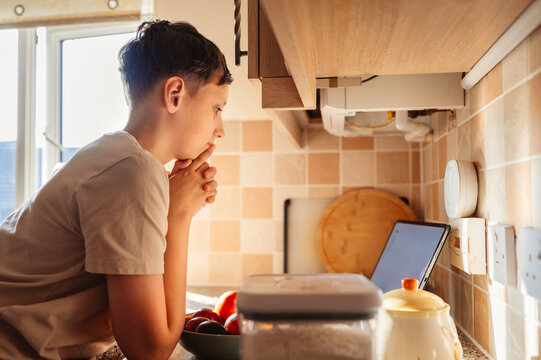 Boy using tablet  while cooking at kitchen counter, digital education.