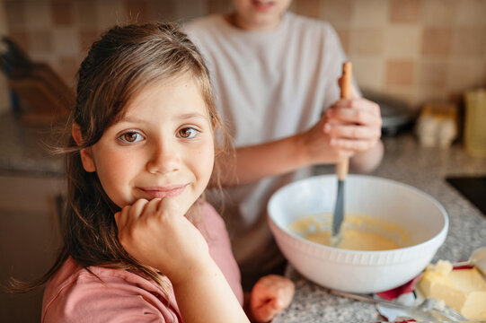 Girl smiling at camera in kitchen during baking, family cooking.