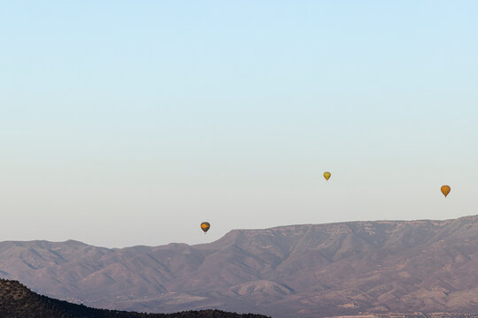 Hot air balloons off center mountainous desert landscape