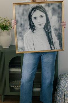 Woman holding framed portrait in living room