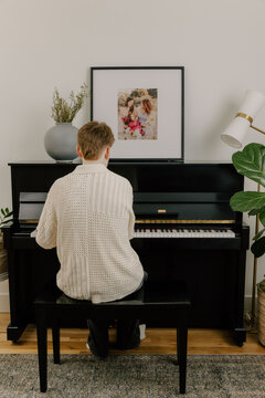 Teenage boy practicing piano at home in modern space