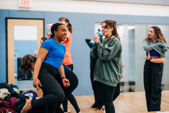 Women laughing and hydrating during fitness class break
