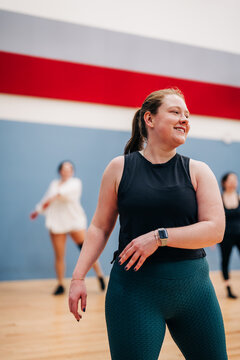 Smiling woman enjoying group dance fitness class indoors