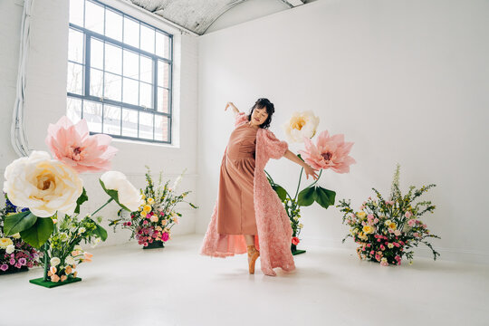 Ballerina dancing gracefully among giant pastel flowers