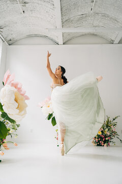 Ballet dancer dancing with flowing skirt in bright floral studio