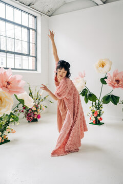 Woman dancing among giant floral decorations in studio
