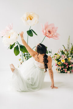 Ballerina posing among giant flowers and blooming floral arrangement