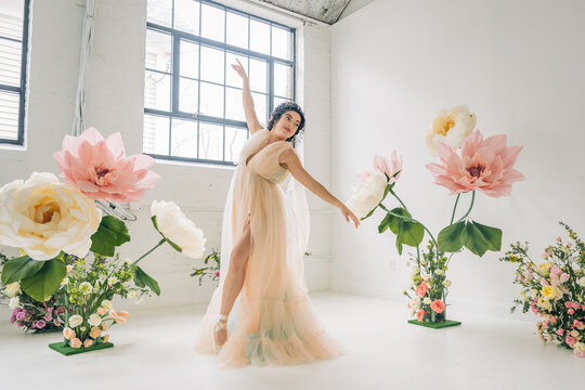 Dancer performing ballet en pointe surrounded by giant paper flowers