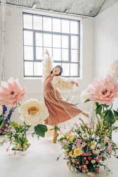 Ballerina dancing gracefully among giant spring flowers