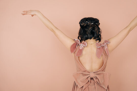 Woman wearing pink velvet dress reaching up