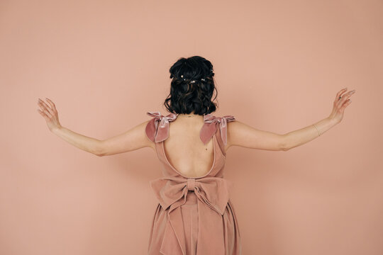 Woman wearing velvet bow dress reaching outward