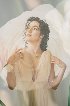 Dreaming woman in ethereal gown with floral overlay