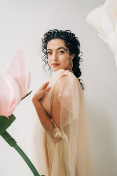 Elegant portrait of woman in soft tulle beside oversized flower