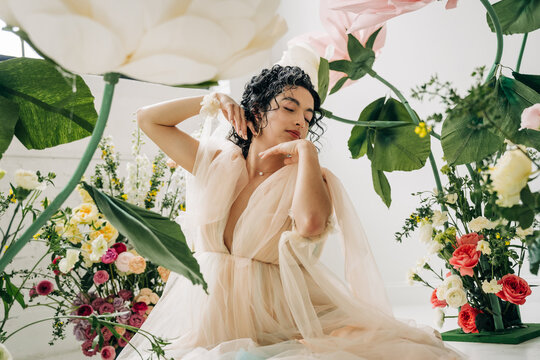 Woman posing with giant flowers in ethereal tulle dress