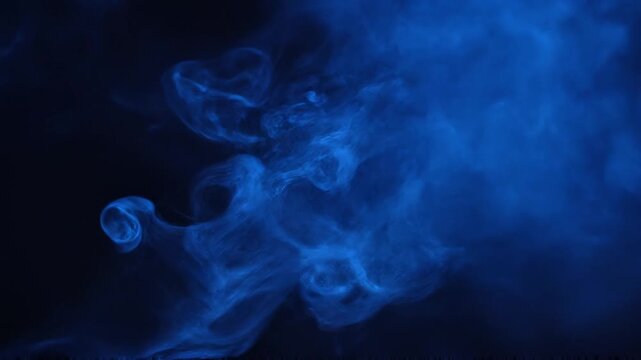 Blue smoke rises in dark air creating mysterious swirling patterns