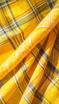 A close-up of a vibrant yellow plaid fabric with a soft, crumpled texture
