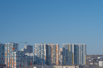 Contemporary city scene with housing. Urban residential area illuminated by winter sunlight. Vivid city environment showcasing modern homes and busy construction sites © beholdereye