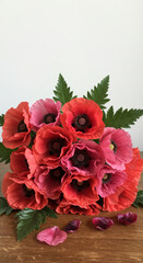 Obraz premium Artistic paper poppies in and pink hues, crafted arrangement, handmade paper flowers, botanical decor, rustic wooden table.